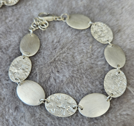 Blättchenarmband mit ovalen Blättchen und Prägung.