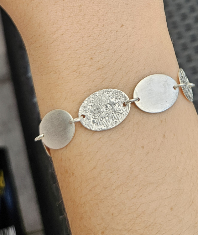 Blättchenarmband mit ovalen Blättchen und Prägung.