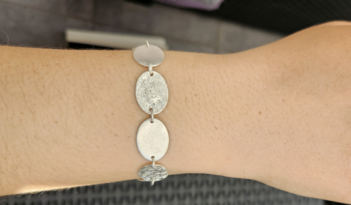 Blättchenarmband mit ovalen Blättchen und Prägung.